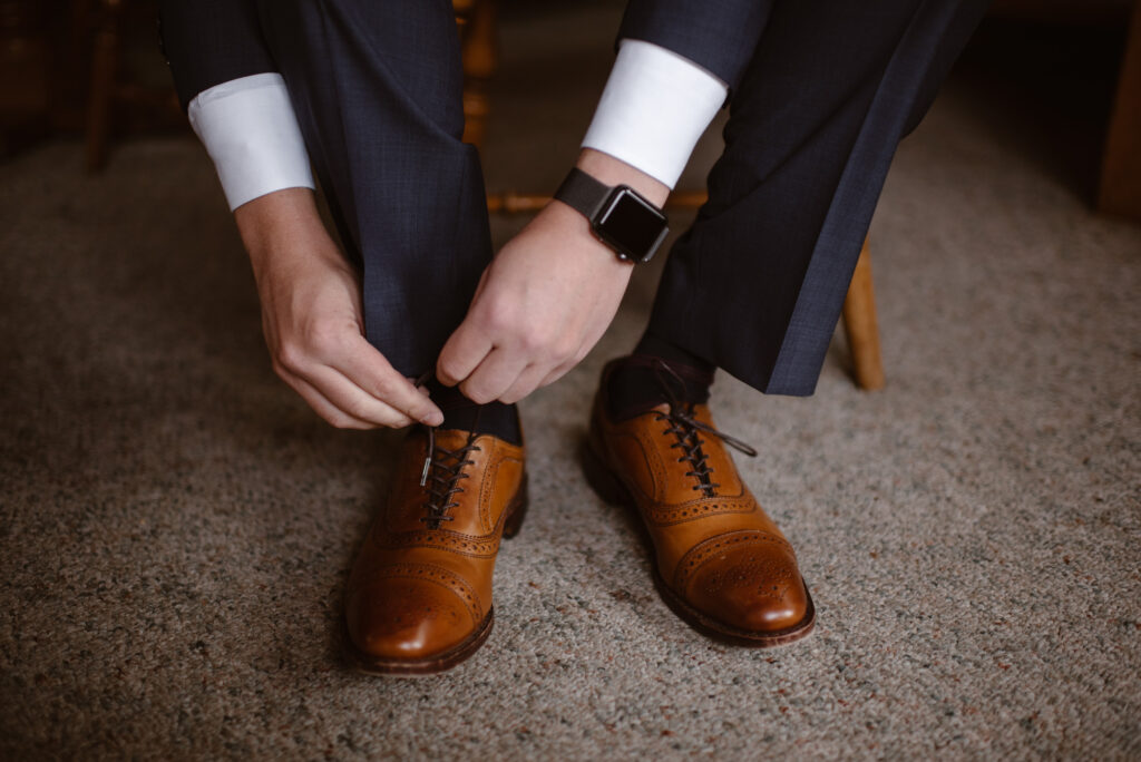 Groom tying his wedding shoes 