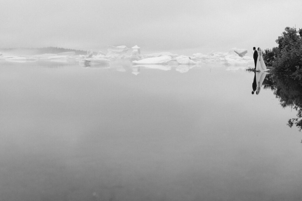 Moody black and white photo of couple at foggy glacial lagoon
