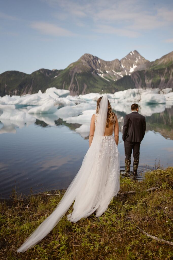 Bride and groom walking through glacial lagoon in Alaska