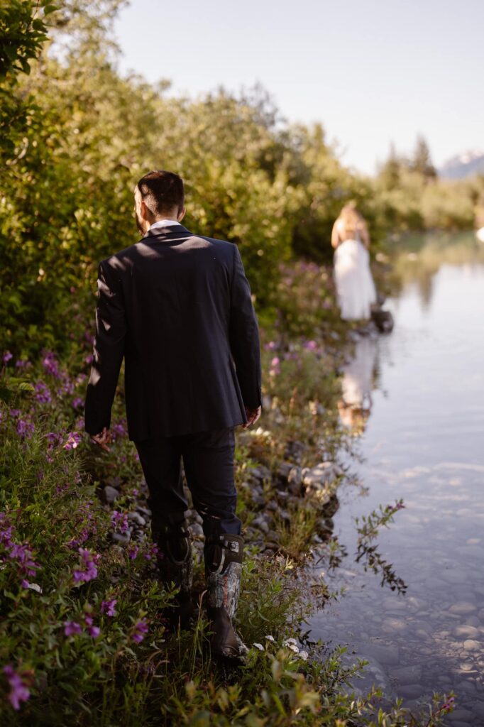 Bride and groom wading through glacial lagoon