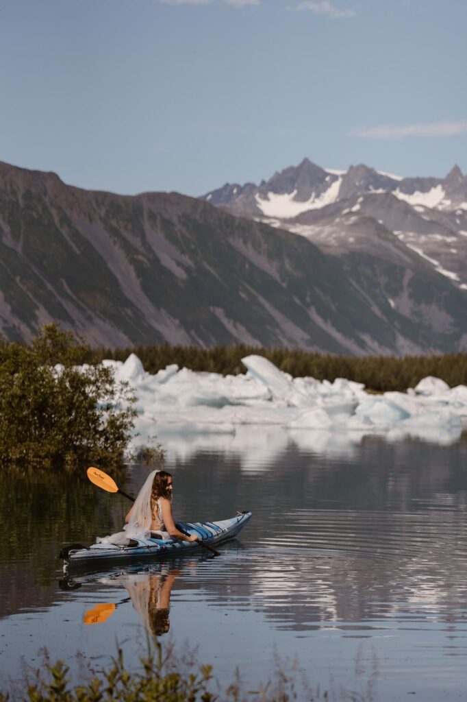 Bride kayaking through glacial lagoon at Alaska helicopter elopement