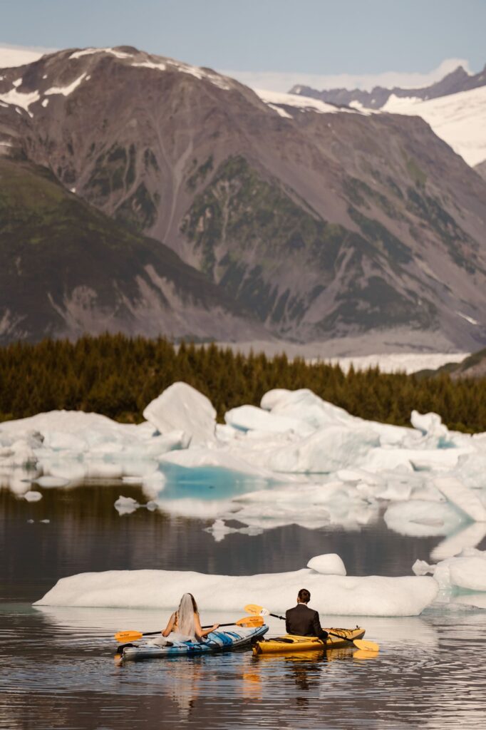 Bride and groom kayaking on their wedding day through icebergs in Alaska
