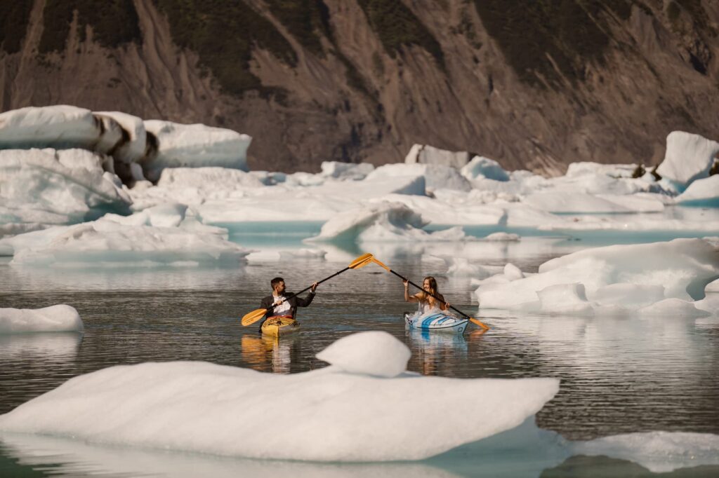 Bride and groom high-fiving paddles while kayaking in Alaska