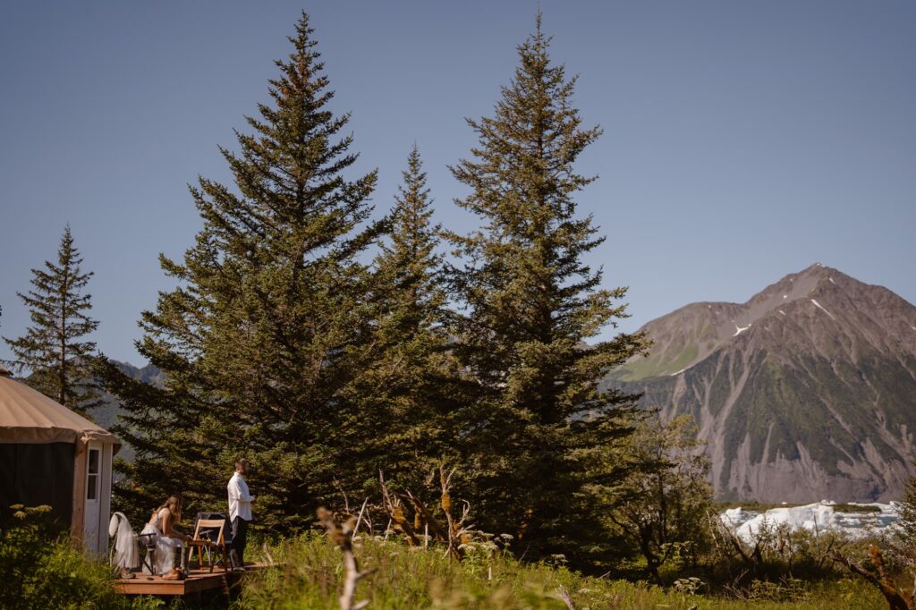 Bride and groom on the deck of their yurt in Alaska at Bear Glacier