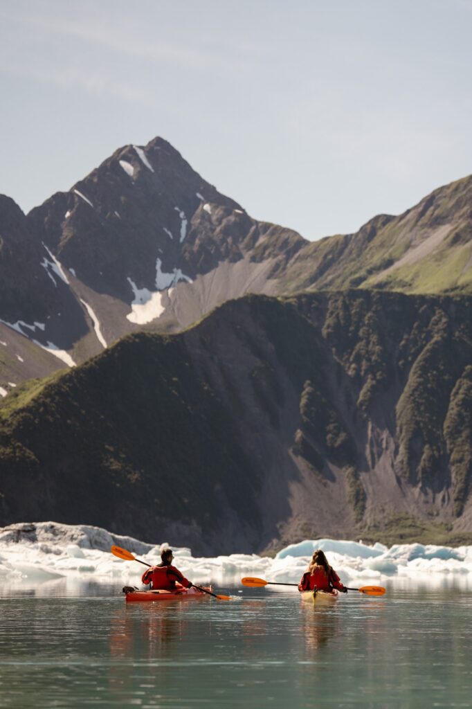 Couple kayaking through glacial lagoon in Alaska