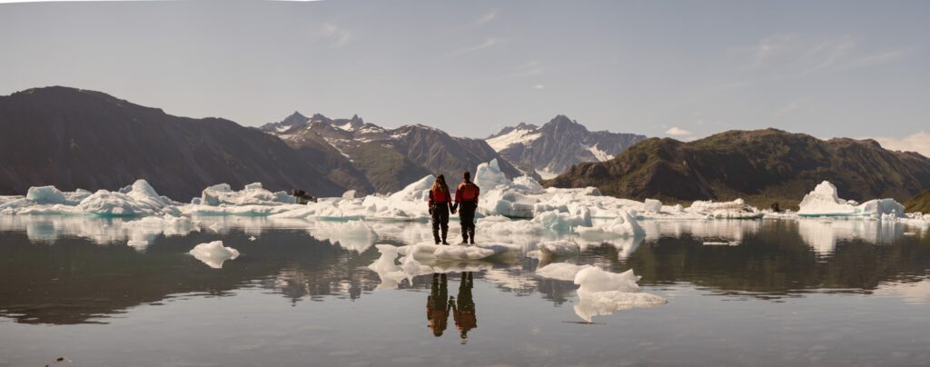 Couple standing on an iceberg during their Alaska adventure elopement
