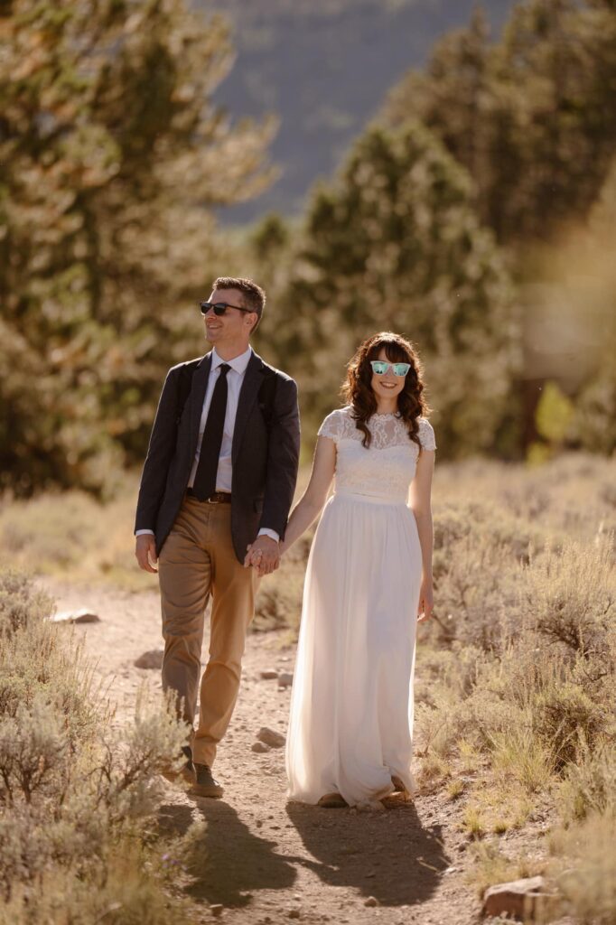 Couple hiking down a dirt trail on their wedding day