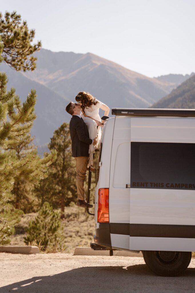 Couple kissing on the back of a camper van during photo session
