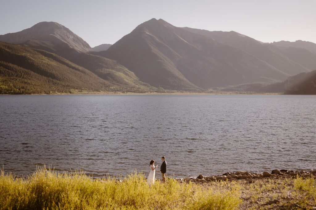 Couple getting married on the shore of a mountain lake at sunset