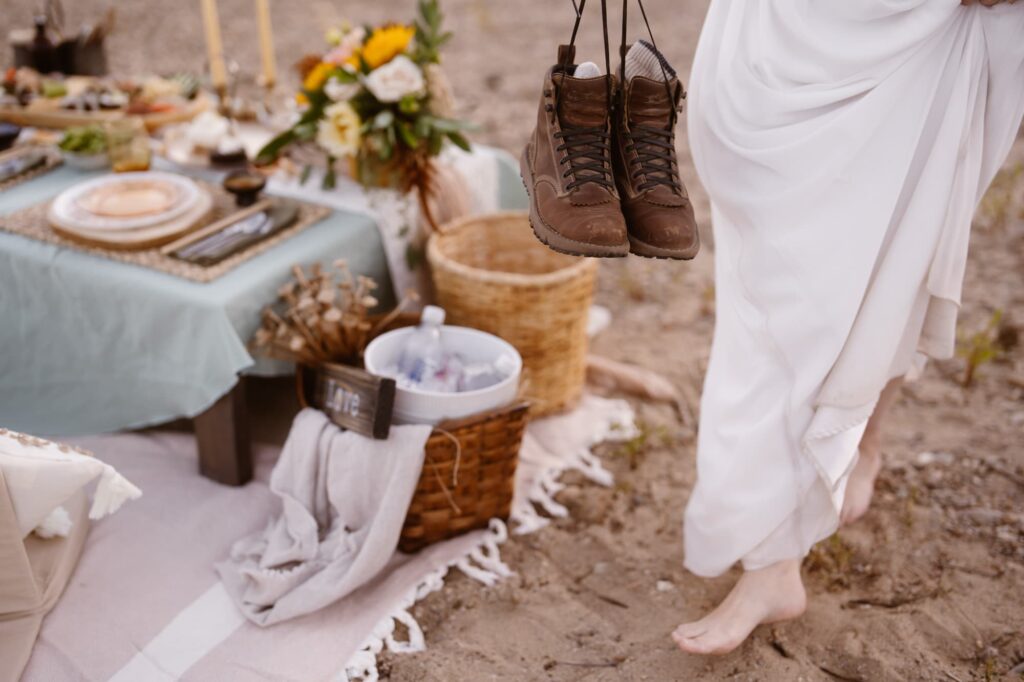 Bride walking barefoot with hiking boots in her hand