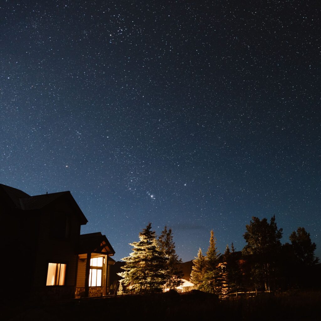 Starry night sky with a glowing house in Crested Butte