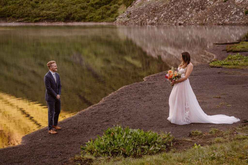 Wedding day first look on shore of alpine lake in Crested Butte