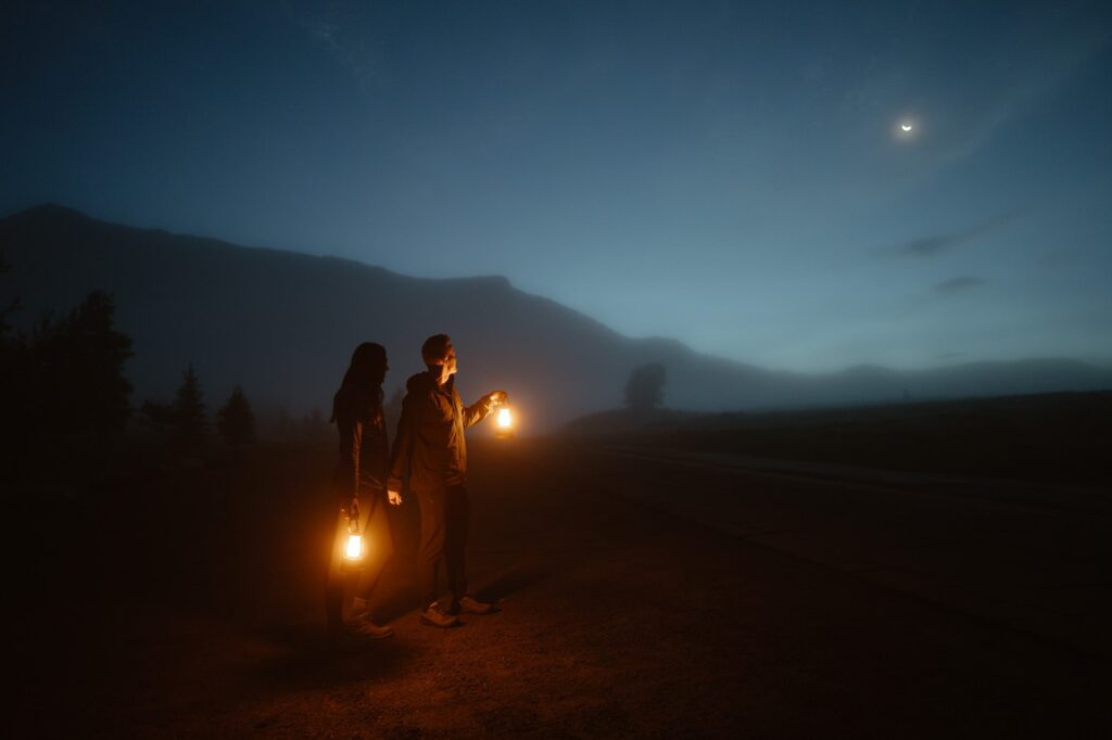 Couple standing with lanterns in foggy scene at night