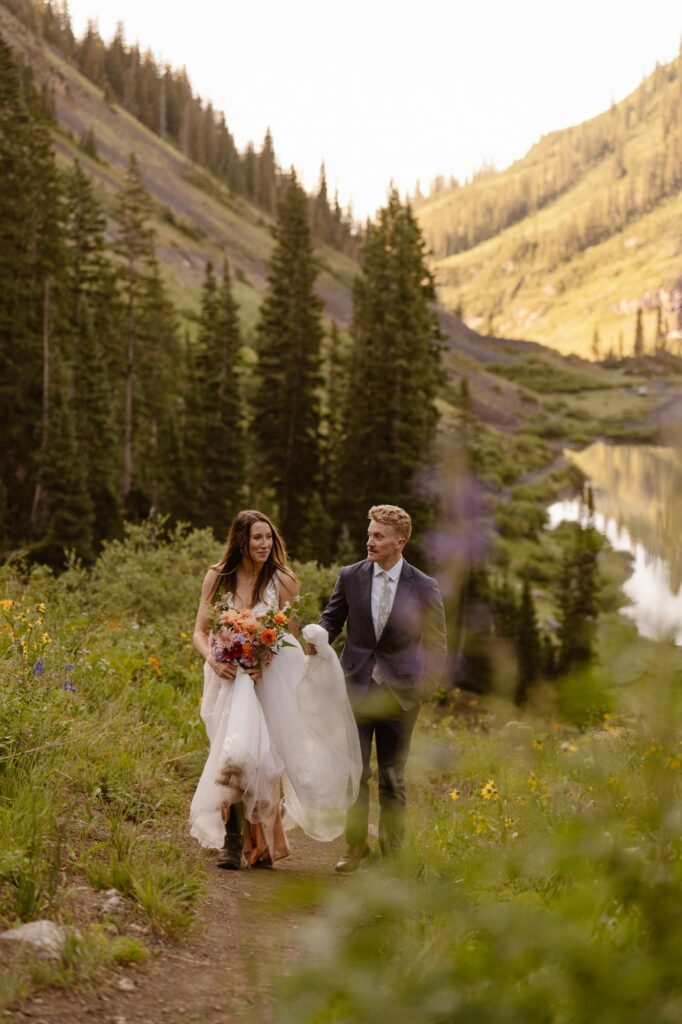 Bride and groom hiking through a trail of wildflowers