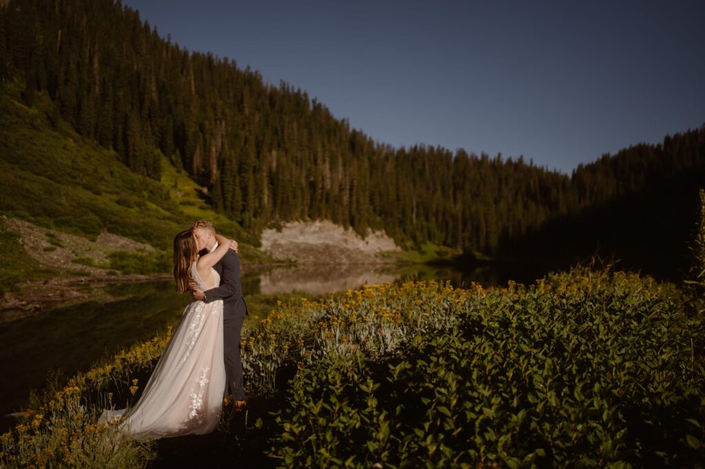 Couple kissing at an alpine lake with yellow wildflowers