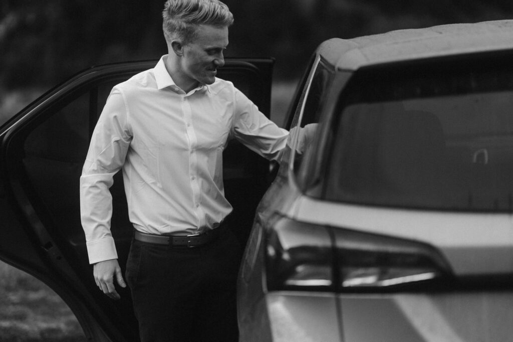 Groom getting ready for his wedding at the car