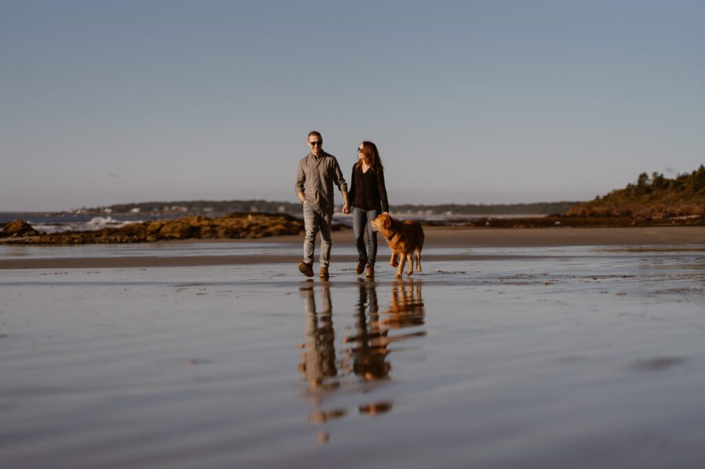 Couple walking down the beach with their dog in Maine