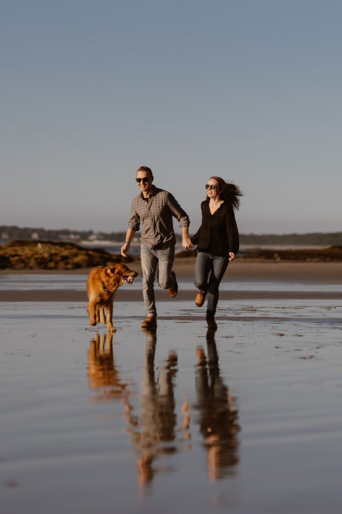 Couple running on the beach with their dog near Portland, Maine