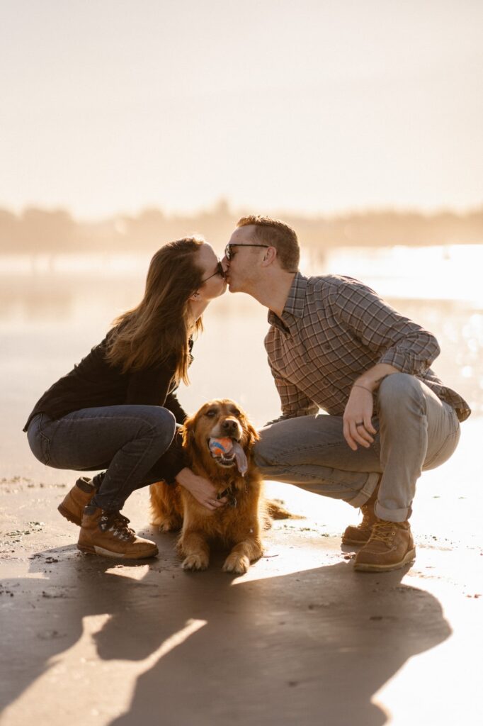 Couple kissing over their dog during lifestyle portrait session