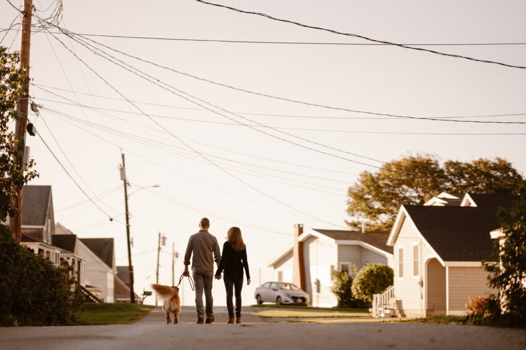 Couple walking dog down the street to a beach in Maine