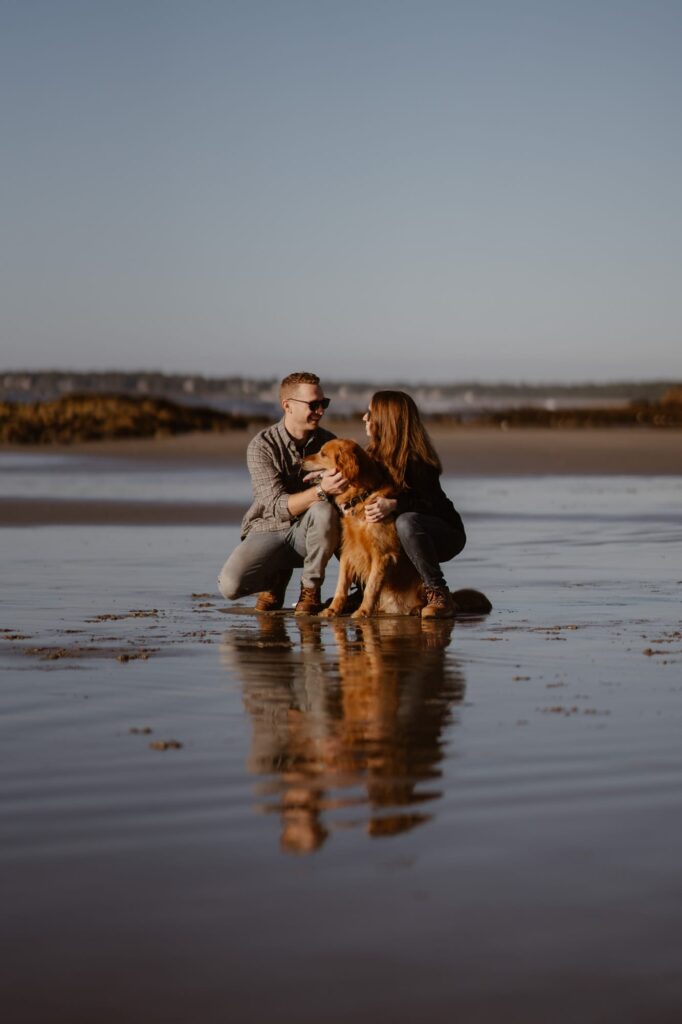 Couple hugging their dog on a beach in Maine during a lifestyle portrait session