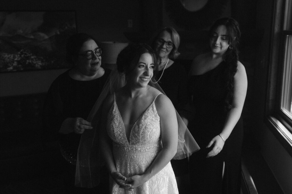 Bride surrounded by her loved ones as she puts on her veil
