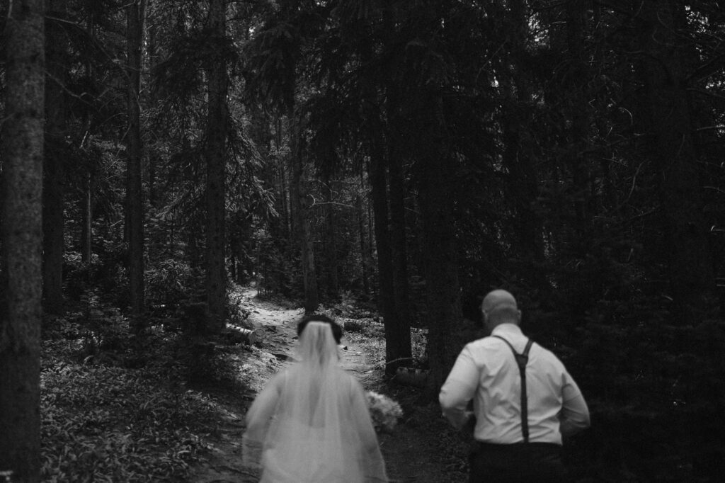 Couple hiking through the forest on their elopement day in Breckenridge