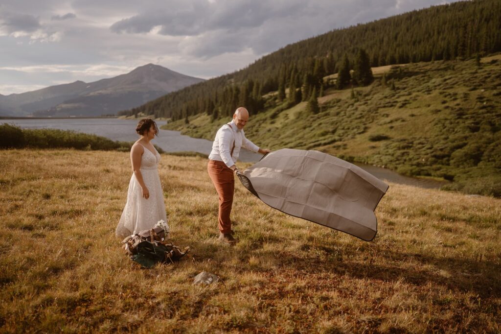 Couple spreading out a blanket on their elopement day