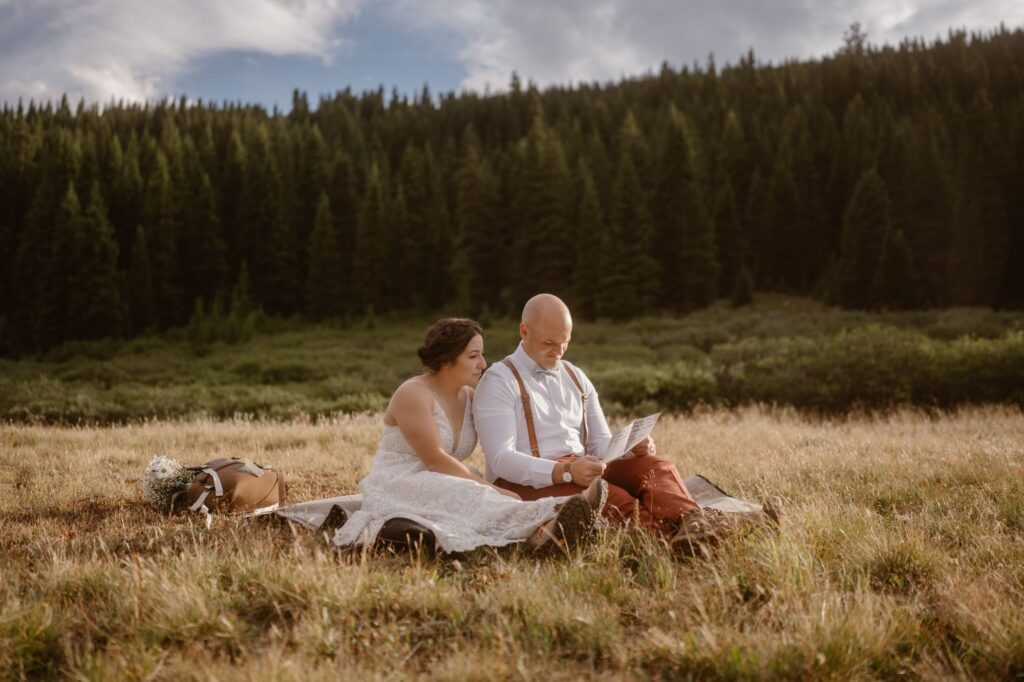 Couple sits in a grassy meadow to read letters from family and friends