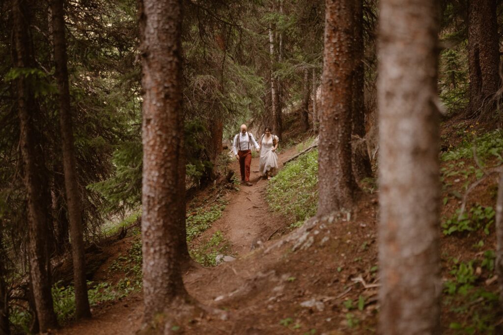 Couple hiking down a forest trail on their elopement day in Colorado