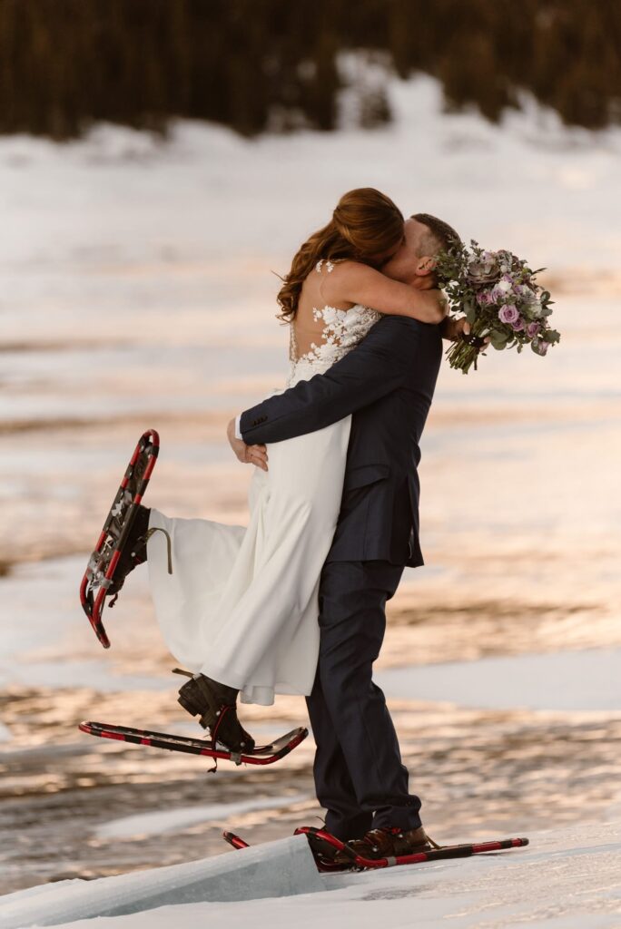 Couple kissing in snowshoes on a frozen lake