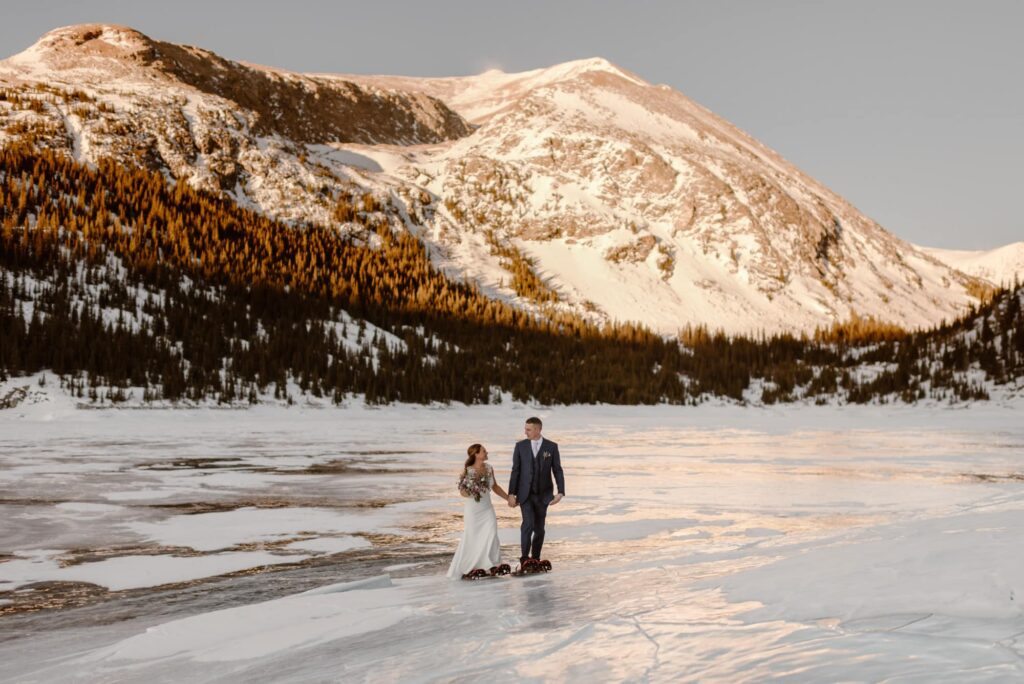 Couple snowshoeing across a frozen lake in Breckenridge, Colorado during their elopement day