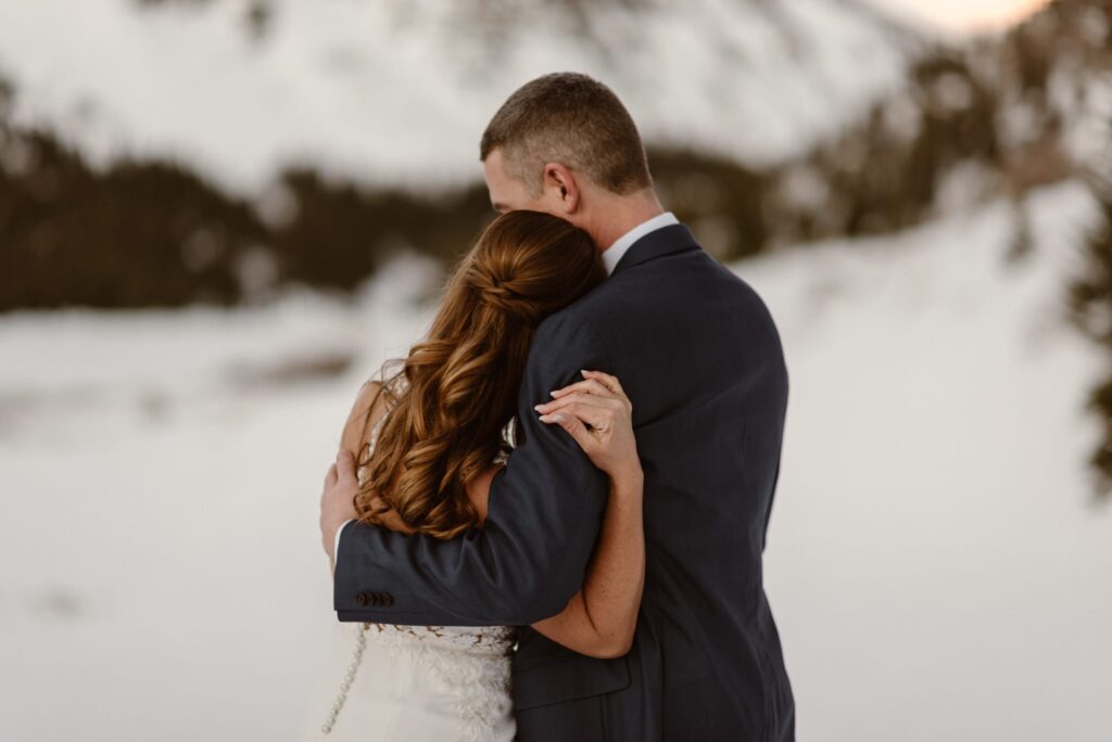 Couple hugging after sharing a first look in the snow