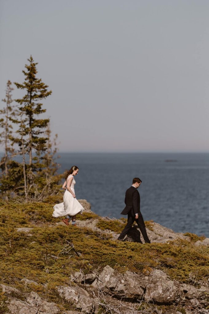 Bride and groom walking down a rocky shore at Isle Royale National Park