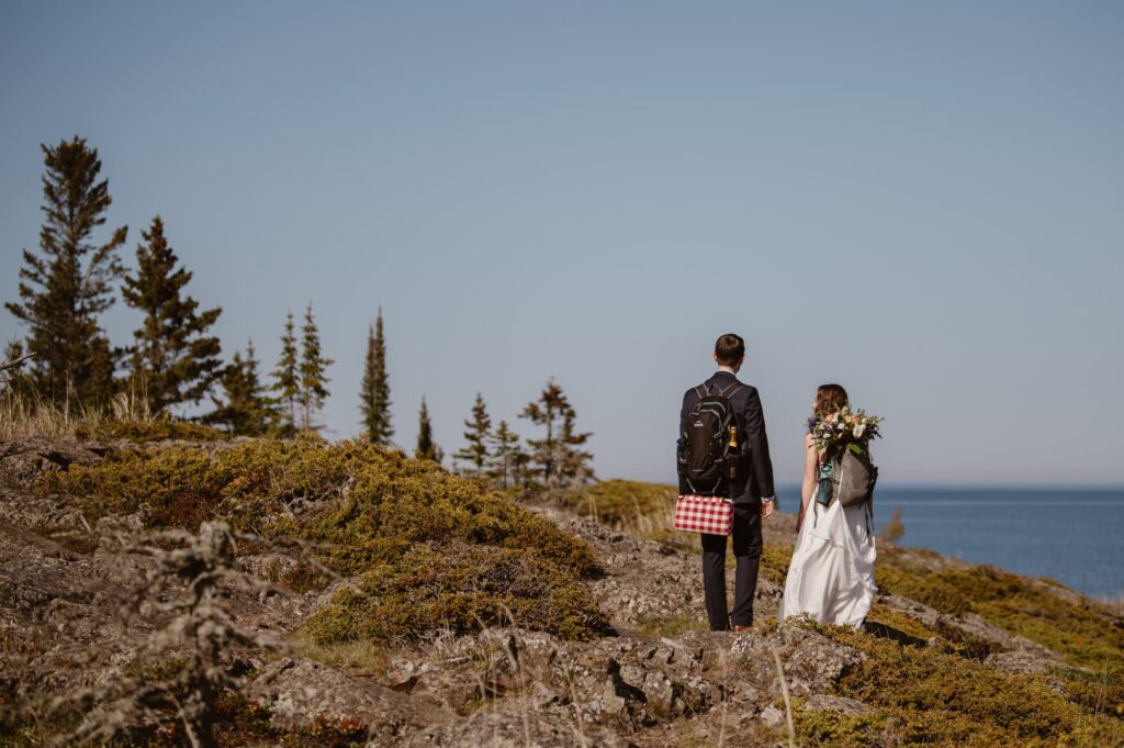 Couple hiking on their elopement day with backpacks and flowers