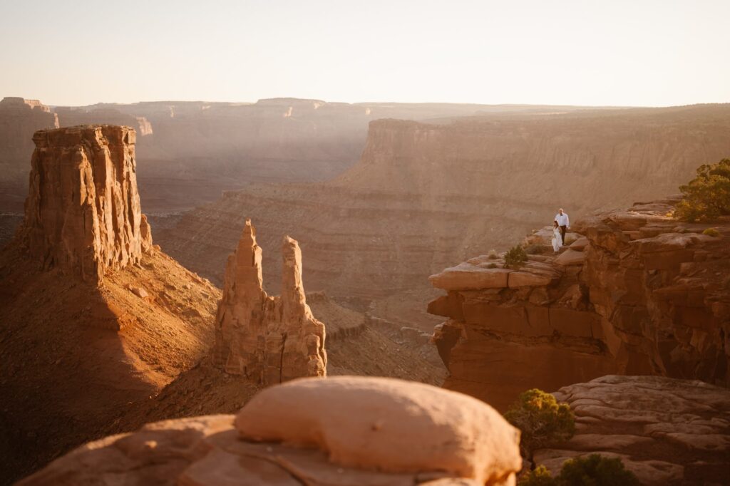 Couple walking to the cliff edge in Moab