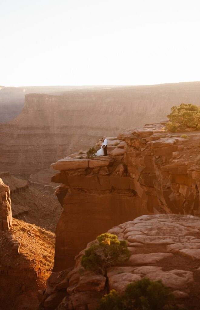 Eloping couple stands on the edge of a cliff in Moab, Utah