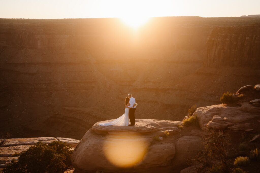 Couple watching the sun set behind the cliffs at the Moab adventure elopement