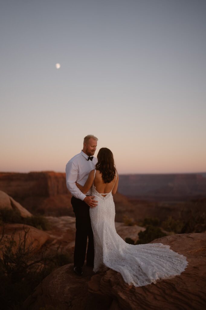Couple on a cliff in Moab Utah with the moon in the background