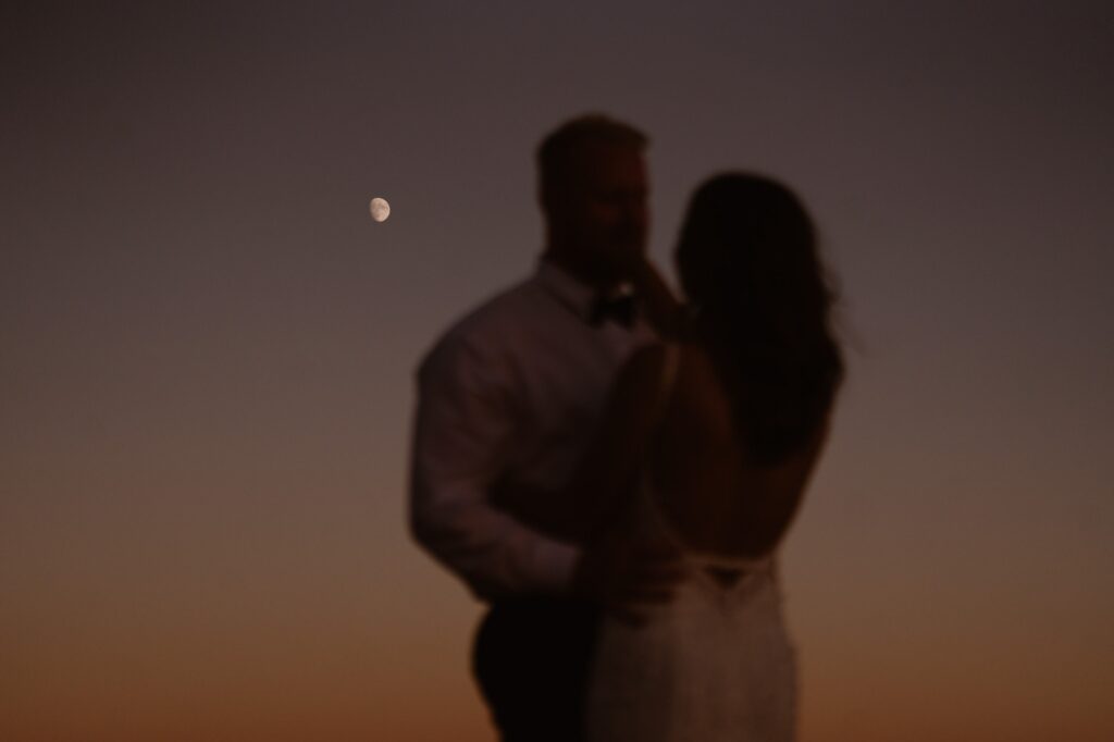 Couple with the moon and a setting sun