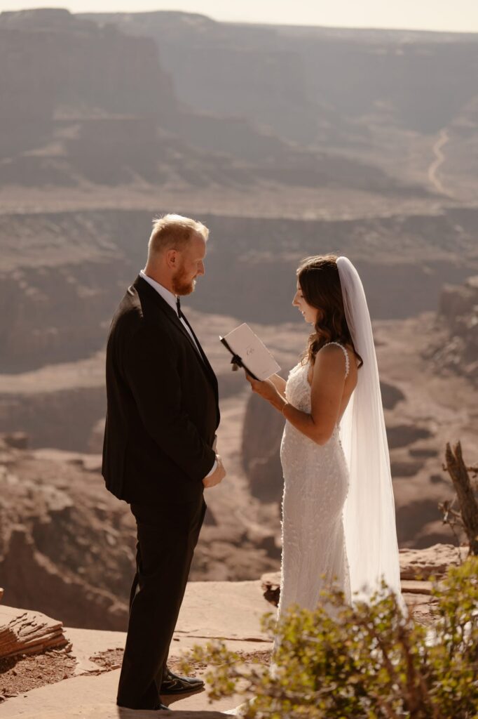 Couple reading vows at the edge of a cliff in Moab