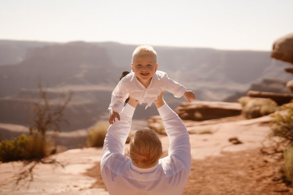 Groom playing airplane with his son after an elopement ceremony at Dead Horse Point State Park