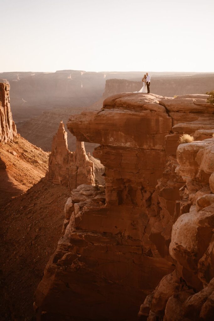 Couple standing on the edge of a huge cliff at sunset