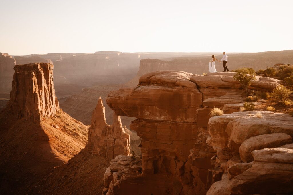 Bride and groom walking to the edge of a cliff