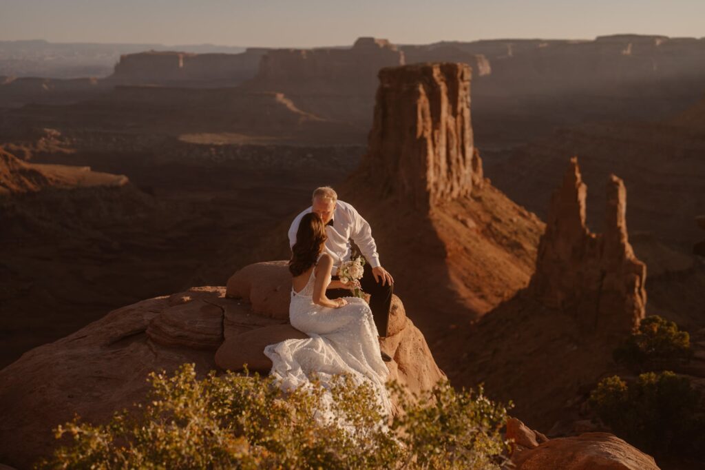 Couple on the edge of a cliff with towers in the background at their adventure elopement
