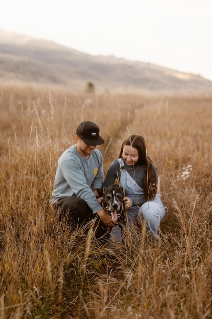 Dog and owners snuggled in the high grass during a lifestyle portrait session