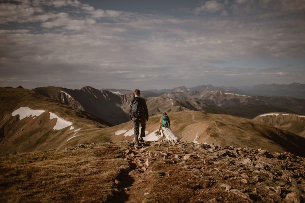 Couple walking down a mountain in their wedding attire