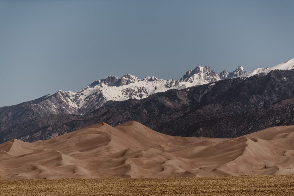 Sand dunes in Colorado with mountain peaks in the background