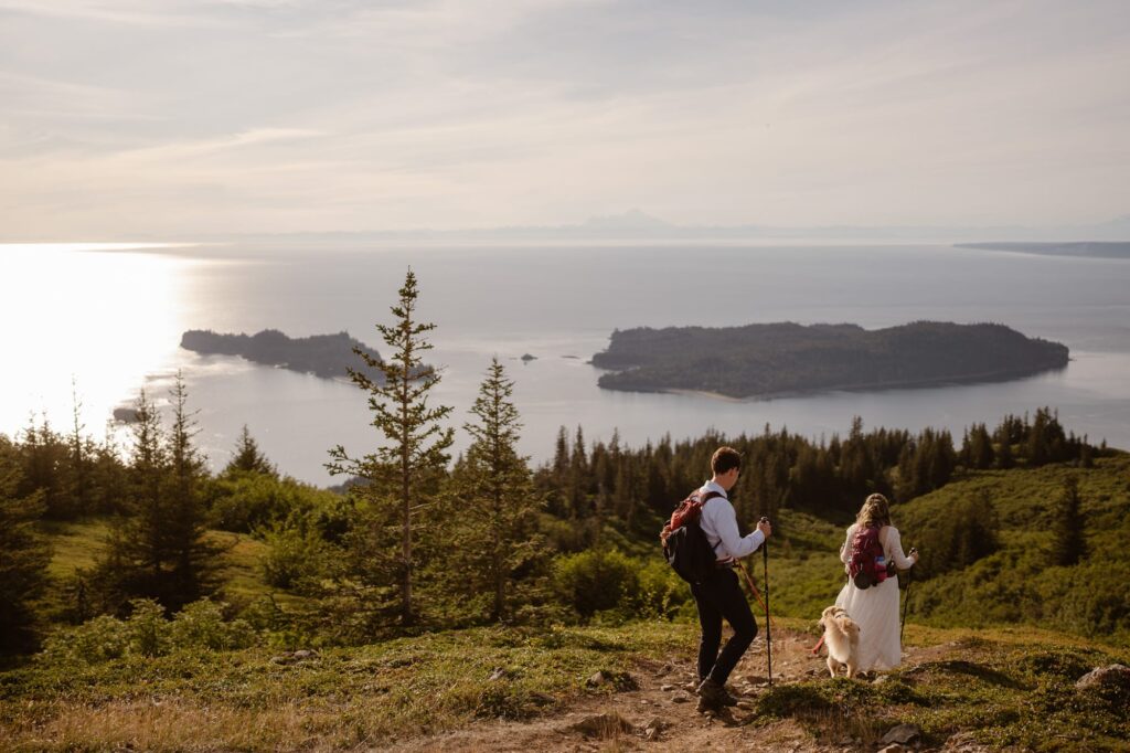View of bride and groom hiking above the ocean in Alaska on their wedding day