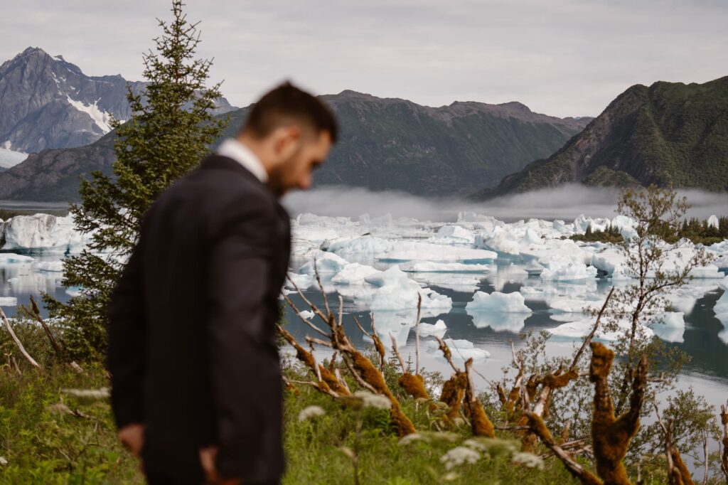 Groom looking off at glacial lagoon before getting married in a remote location 